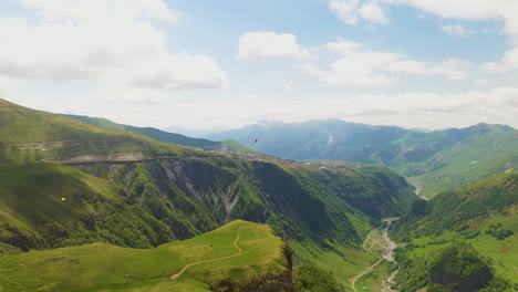 Tracking-wide-drone-shot-of-a-paraglider-in-the-Caucasus-mountains-in-Gudauri-Georgia