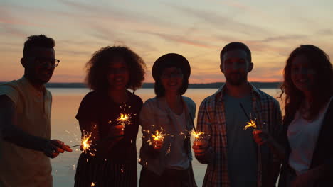friends celebrating at sunset by the lake with sparkler