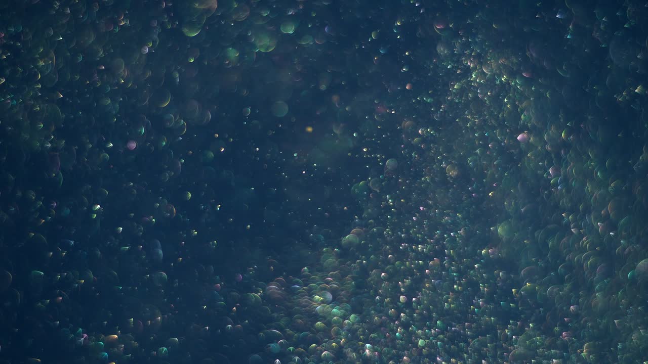 Light seamless transparent bubbles swirling and circling randomly in the air on dark cosmos background.