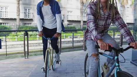 two diverse male friends riding bicycles in street