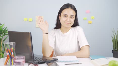 una estudiante saludando a la cámara.