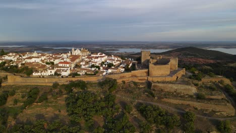 drone sigue una muralla medieval alrededor de la ciudad del castillo de monsaraz con paredes blancas y techos de tejas