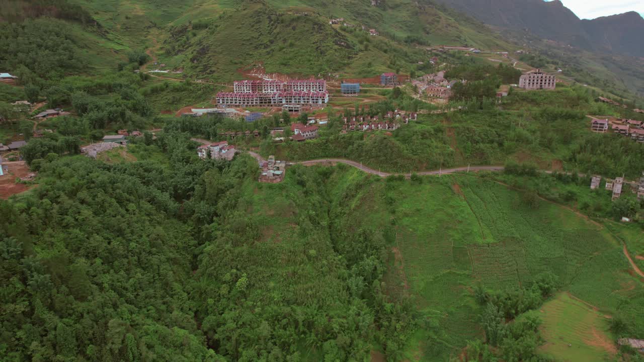 imágenes panorámicas de drones: círculo aéreo sobre un pueblo de montaña verde con conaca, casas y red de carreteras de conexión, capturando la belleza rural