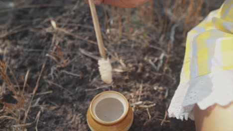 toma de primer plano en cámara lenta mientras una bonita mujer india sumerge el borde de un cepillo en un frasco de pegamento y lo lleva al borde de una olla de barro rota