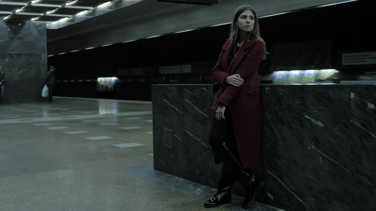 женщина ждет на станции метро.