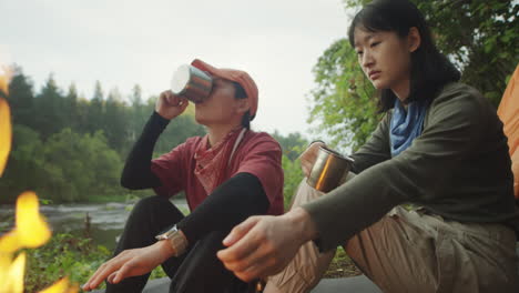 female tourists warming hands over campfire