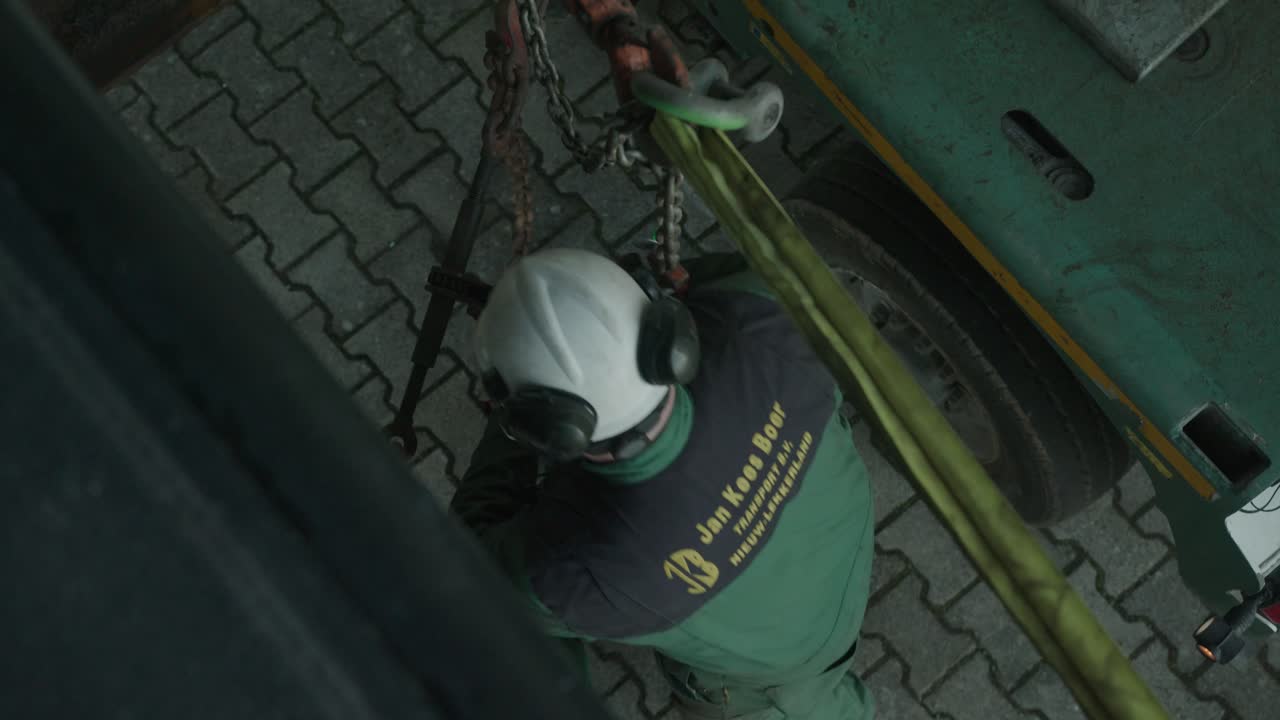 trabajador en un casco apretando cables de acero para el transporte de maquinaria grande, vista superior