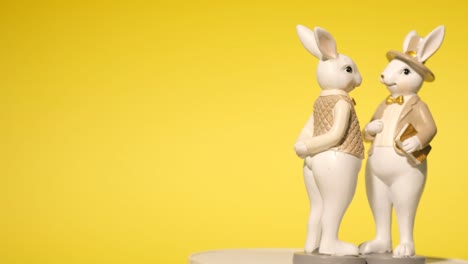 close-up, ceramic toy in the shape of easter bunnies on a yellow background. place for text. 4k video