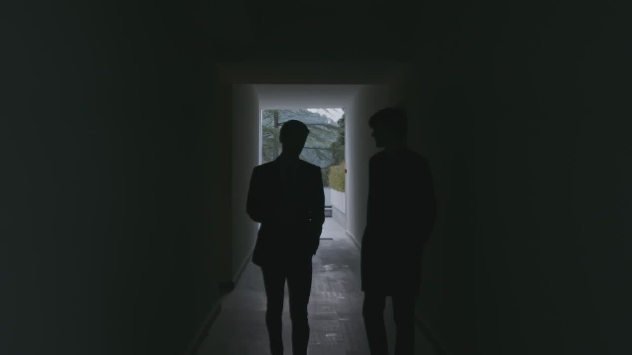 dos hombres de negocios caminando por un corredor oscuro