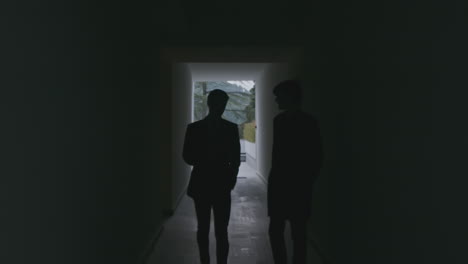 two businessmen walking down a dark corridor