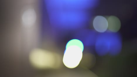 luces nocturnas desfocadas de la ciudad en el distrito comercial de parís. fondo de un rascacielos. color borroso bokeh de los edificios. rastrear. 4k uhd. azul y amarillo.