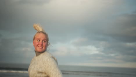 young blonde woman runs athletically along the shore and looking back laughing