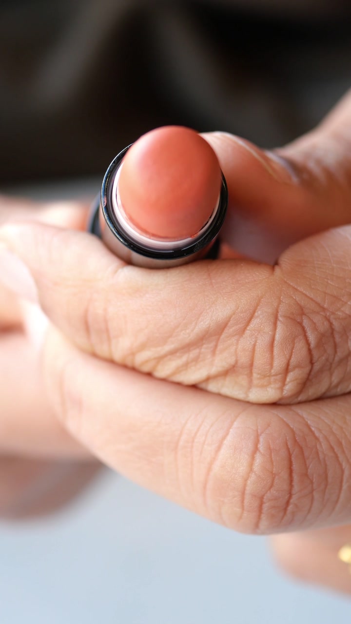 Close-up of Hands Twisting Up a Peach Lipstick