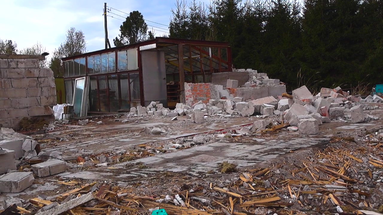 Struttura distrutta con detriti di cemento, assi di legno e mattoni sparsi nel cantiere dopo la demolizione di un edificio, lasciando dietro di sé una scena di degrado urbano e rovina.