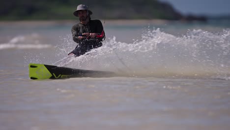 slomo telefoto de un kiteboarder haciendo una transición al otro lado en aguas poco profundas