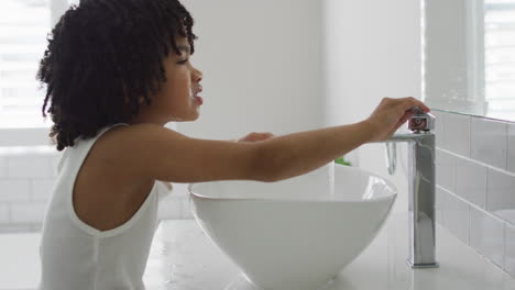 biracial boy washing hands in a bright bathroom