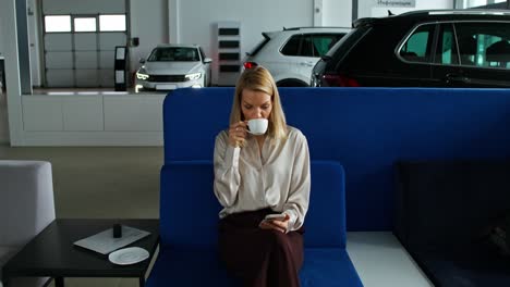 woman browsing smartphone in car dealership waiting area