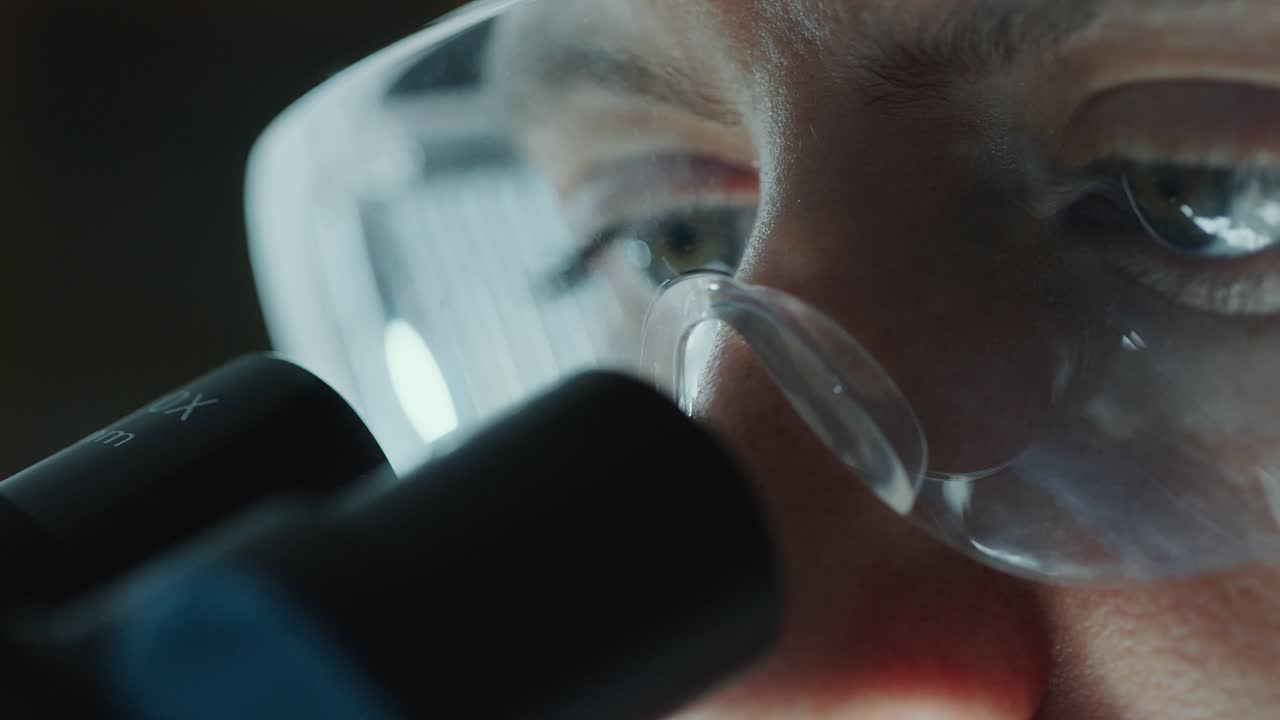 Eyes of Female Scientist in Protective Goggles Looking into Lab Microscope