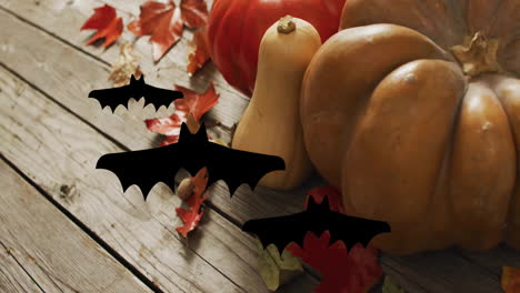 pumpkins and autumn leaves with flying bats animation over wooden background