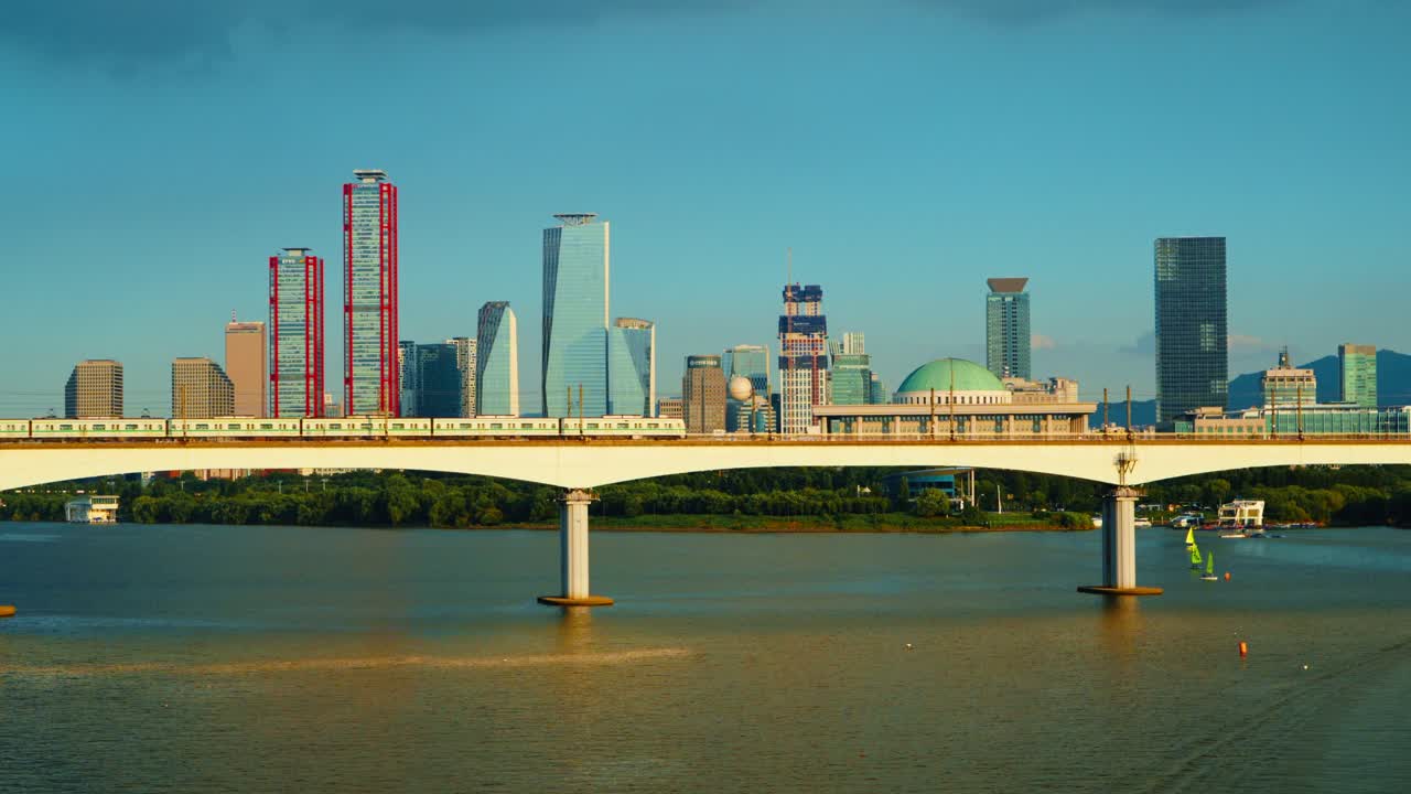Metro train crosses Dangsan Railway Bridge in Seoul with golden sunset sunlight reflecting on its surface and bouncing onto the Han River below, Yeouido financial district in backdrop
