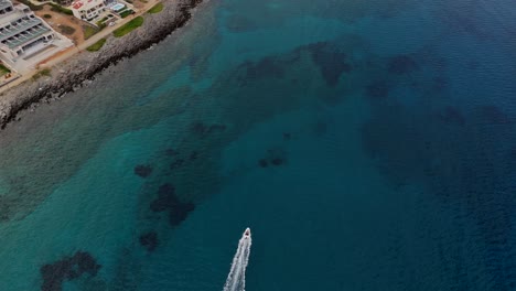 aerial - fast-moving boat near rocky coast in crete greece with clear blue waters