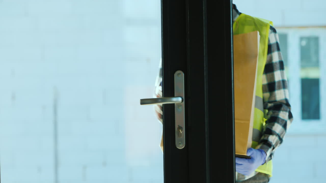 자원봉사자가 자가격리 중인 가족에게 음식 가방을 가져다 줍니다.