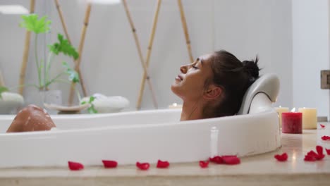 mixed race woman lying in a bathtub at home