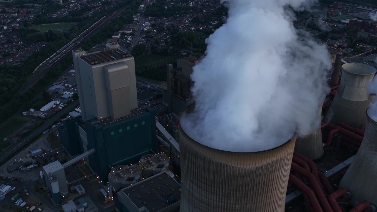 Vista aerea della centrale elettrica di Niederausem in Germania al tramonto, che mostra una massiccia centrale a combustibili fossili con torri di raffreddamento fumanti e infrastrutture energetiche industriali