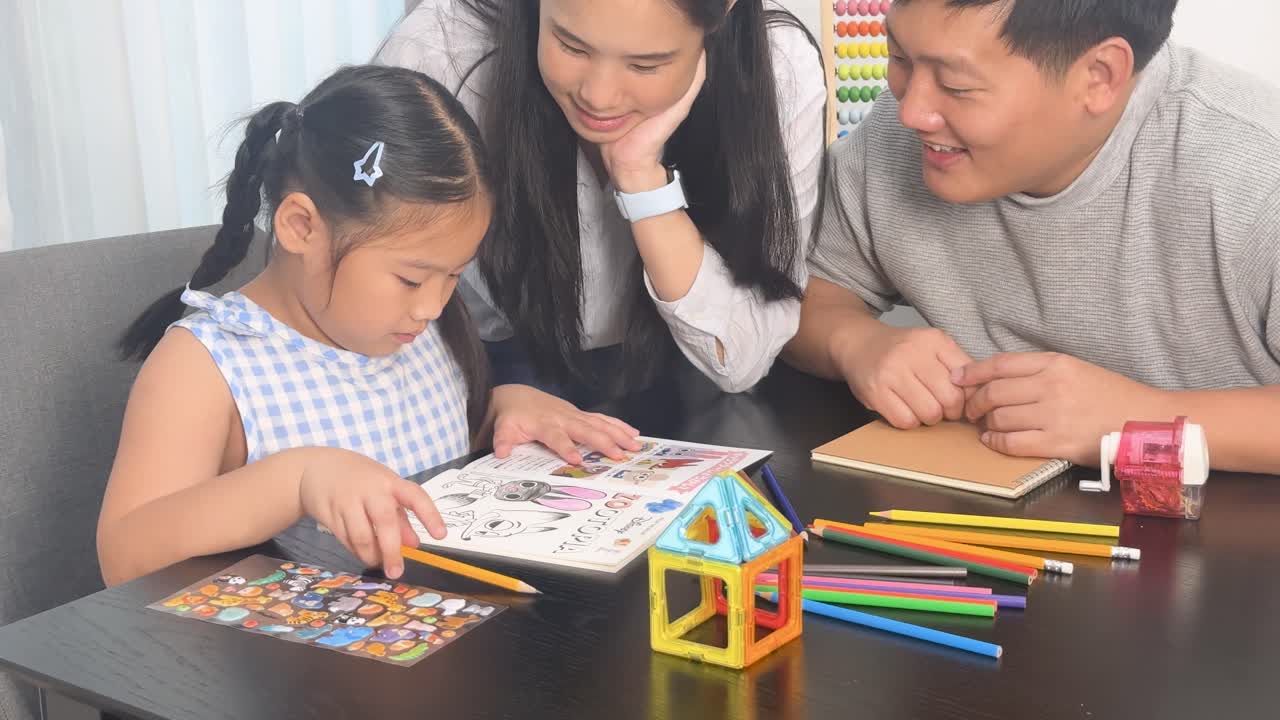 A young girl receives help from her parents with homework, surrounded by colorful pencils and stickers in a cozy setting