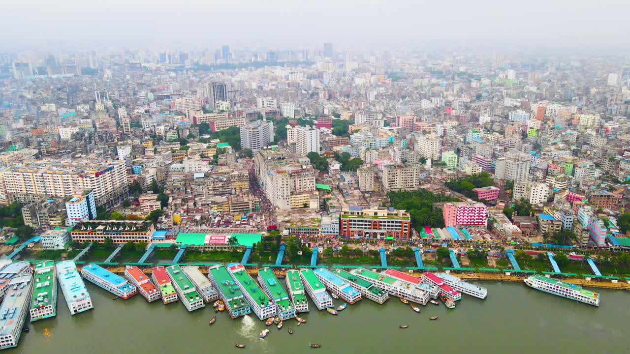 Aerial of Dhaka City skyline with cargo ships and boats on the Buriganga River on a foggy day