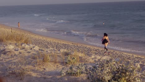 mujer caminando por una playa al atardecer