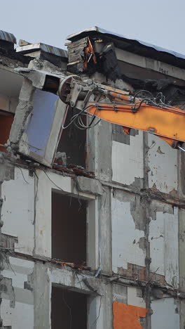 urban excavator destruction demolishing. demolition building after nature disease. vertical video