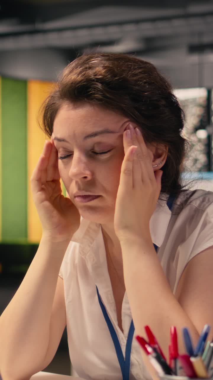 Video verticale: donna d'affari che soffre di mal di testa e affaticamento visivo mentre lavora in un ufficio aziendale.