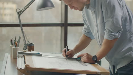 A male architect creates a drawing of a building on paper. To study the design of premises to create furniture and houses. Large modern office draw on blackboard.