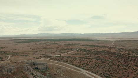 Aerial-footage-of-following-a-dirt-road-beside-a-mountain