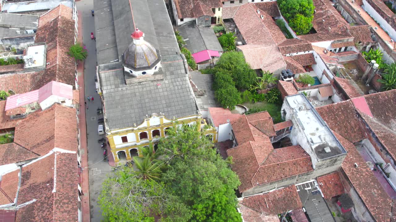 The drone glides above the rooftops in the heart of Mompox, revealing the intricate colonial architecture that defines this historic town. Pitch forward with jaw left.
