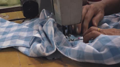 una costurera trabajando en una camisa usando una máquina de coser cerca