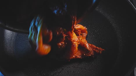 putting seasoned chicken breast into pan for cooking