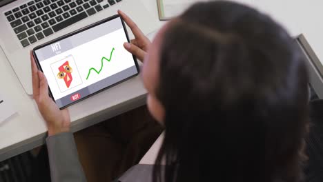 mujer de negocios biracial que usa una tableta para videollamadas con procesamiento de datos