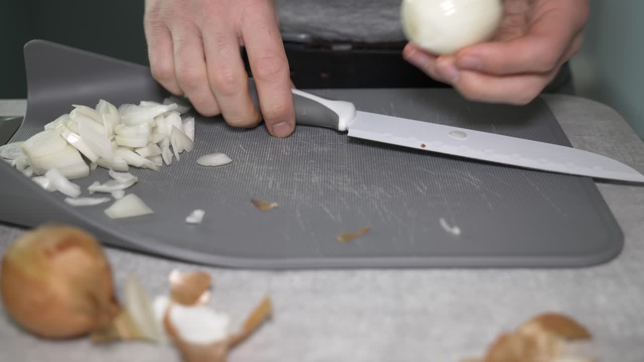 A man peeling and chopping onion at home