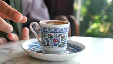 cerca de una mano sosteniendo una tradicional taza de café turca