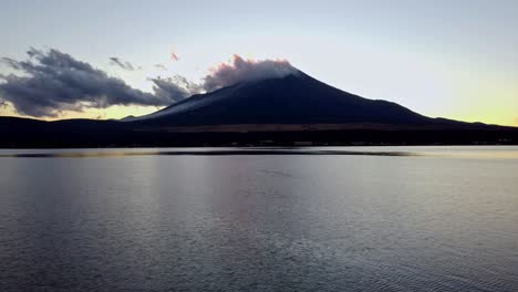 Die-Morgendämmerung-Bricht-über-Dem-Ruhigen-Wasser-An,-Im-Hintergrund-Der-Fuji,-Sanft-Vorbeiziehende-Wolken