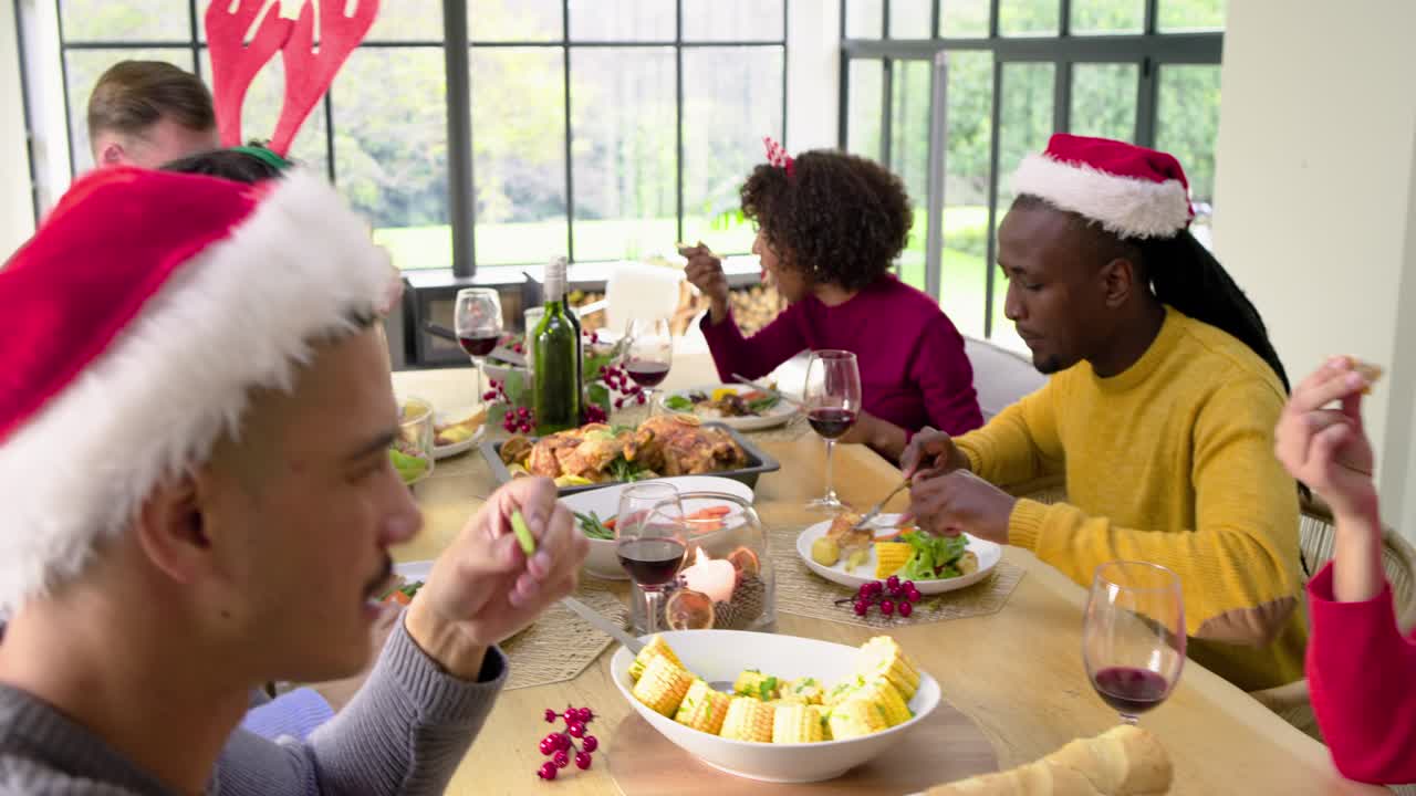 Toasting wine during holiday diverse friends smiling and eating salad and bread at dining table