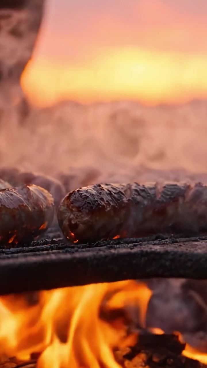 Grigliare Salsicce Saporite su un Letto di Carboni Ardenti al Tramonto, Catturando la Succulenza Sfrigolante e l'Aroma Affumicato nell'Ora d'Oro
