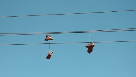 wide shot of old sneakers dangling by their laces over a wire