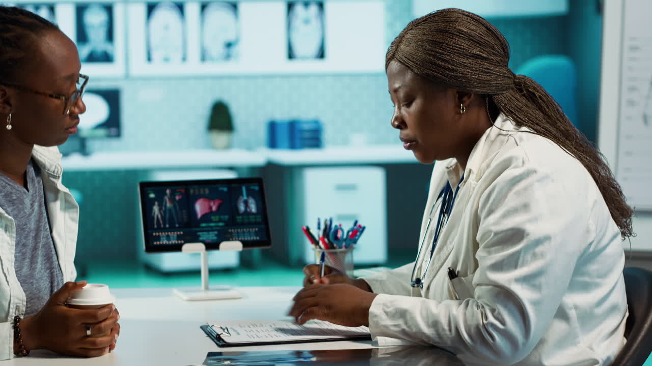 Female general practitioner examining medical data with a patient
