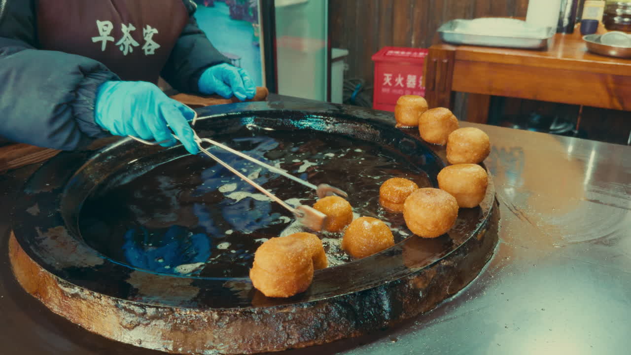 Street food vendor frying round dumplings