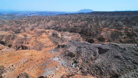 birdseye view of rugged terrain at the gorafe desert in granada, spain, tilting up to the horizon to reveal the landscape