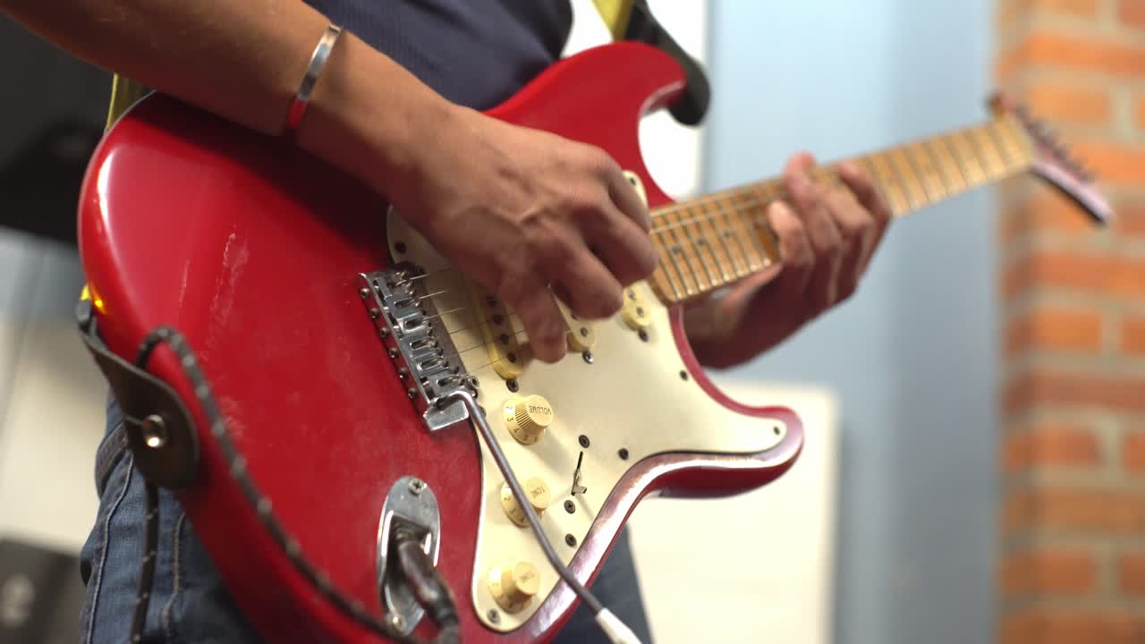 hombre tocando una púa en una guitarra eléctrica roja