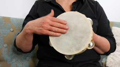 Forward-facing-view-of-a-woman-playing-a-tambourine,-static-handheld